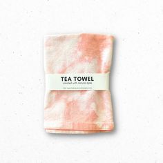 the tea towel in pink and white is folded on top of a white surface with a tag