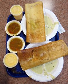 two plates with some food on them and sauces next to one plate that is half eaten