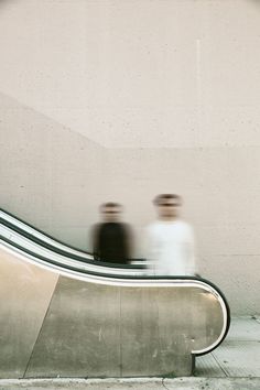 two people riding on an escalator in front of a sign that says lacma