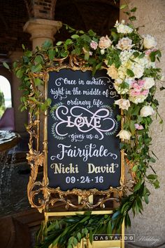 a chalkboard sign decorated with flowers and greenery