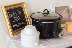 a black crock pot sitting on top of a table next to a chalkboard sign