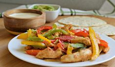 a white plate topped with chicken and veggies next to tortilla chips