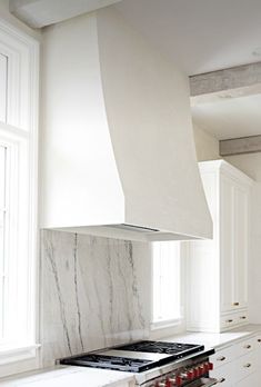 a stove top oven sitting inside of a kitchen next to white cabinets and counter tops