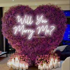 a heart - shaped display with candles in front of it that says will you marry me?