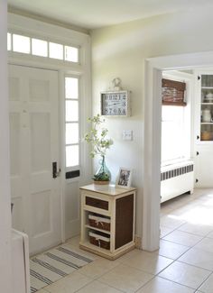 a room with a door, table and vase on the floor in front of it