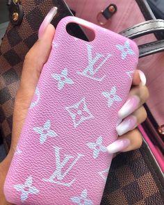 a woman's hand holding a pink phone case with white designs on the back