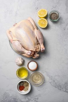 raw chicken, lemons, spices and seasonings on a gray background