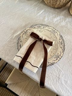 the table is set with white linens and brown ribbon