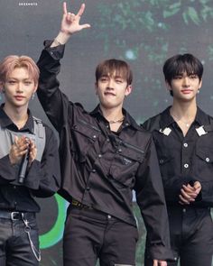 three young men standing next to each other in front of a green and black background