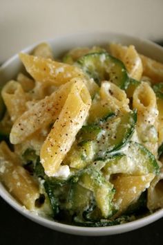 pasta with zucchini and spinach in a white bowl on a black table