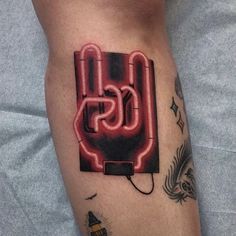 a man with a neon sign tattoo on his leg that reads css and is plugged in