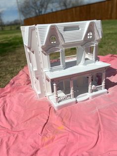 a white doll house sitting on top of a pink sheet