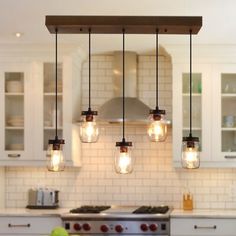 a kitchen with white cabinets and lights hanging from the ceiling