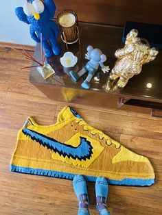 a pair of blue and yellow shoes sitting on top of a wooden floor next to a teddy bear