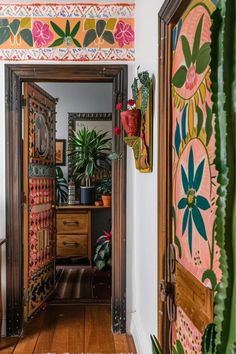 an open door leading to a room with plants on the wall and potted cacti