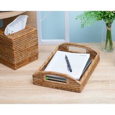 a desk with a pen and paper holder on top of it next to a plant