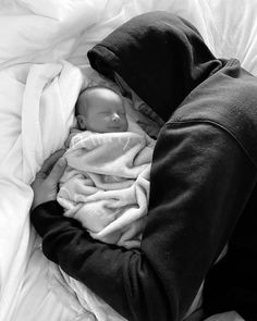 a baby wrapped in a blanket laying on top of a bed