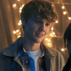 a young man is standing in front of christmas lights