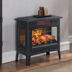 an electric stove with logs in it on the floor next to a lamp and rug