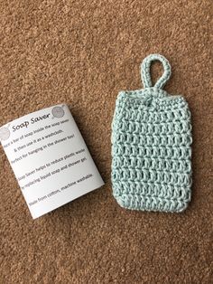 a crocheted bag with a tag attached to it sitting on the floor next to a card