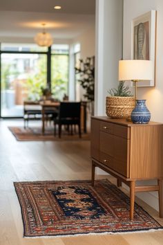 a living room with a rug, table lamp and pictures on the wall above it