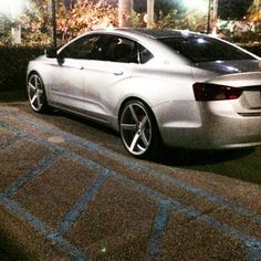 a silver car is parked on the side of the road at night with its lights on