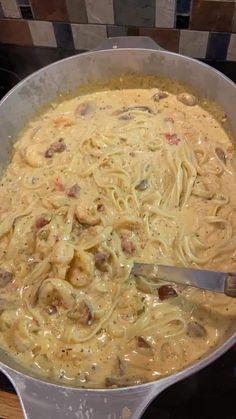 a large pot filled with pasta and meat on top of a stove next to a wooden table