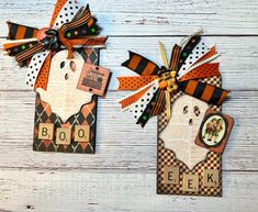 two halloween tags with the words boo and eek on them, hanging from wooden boards