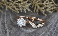 two wedding rings sitting on top of a wooden table next to some plants and branches