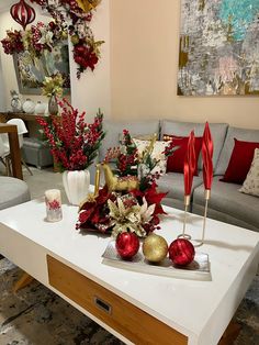 a living room decorated for christmas with red and gold ornaments on the coffee table in front of it