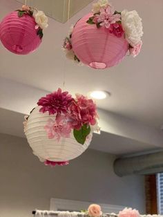 three pink and white paper lanterns hanging from the ceiling above a dining room table with flowers on it