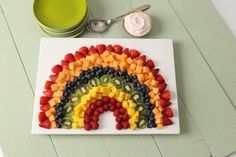 a white plate topped with fruit next to a bowl of yogurt and a spoon