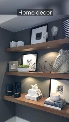 some shelves with books, pictures and other items on them in a room that is painted gray