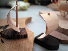 two wooden model boats on a table with other woodworking tools in the back ground