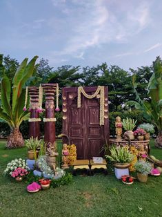 a wooden door surrounded by potted plants and other decorative items on the grass in front of it