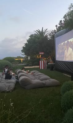 two people sitting on bean bags in front of a movie screen and watching the movies