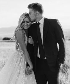 a man in a suit and tie kissing a woman in a wedding dress on the field