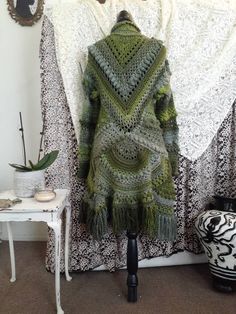 a green shawl draped over a mannequin in front of a white wall