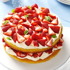 two cakes with strawberries on top are sitting on a plate, one is white and the other is yellow