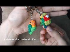 two small crocheted parrots are being held by someone