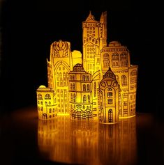 some paper houses are lit up in the dark with yellow lights on them, and one is