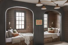 two twin beds in a room with arched windows and plaid wallpaper on the walls