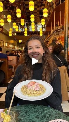 a woman sitting at a table with a plate of food in front of her