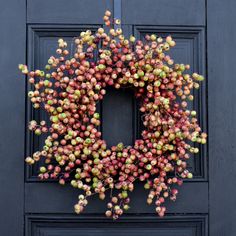 a wreath on the front door of a building with fruit hanging from it's sides