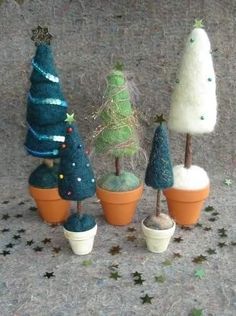 there are many small trees in pots on the table and one is made out of clay