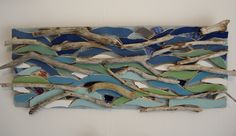 a piece of art made out of driftwood and blue glass with seaweed on it