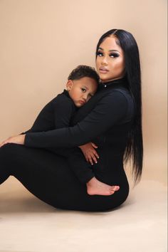 a woman sitting on the ground holding a child in her lap and posing for a photo