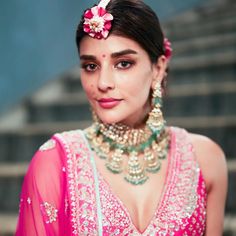 a woman in a pink outfit with flowers on her head and jewelry around her neck