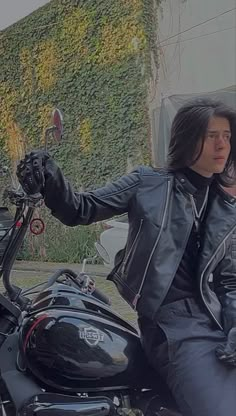 a man in black leather jacket sitting on a motorcycle with his hand out to the side