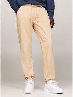 Tommy Hilfiger men's pant. Designed to be worn anywhere, these slim-cut, stretch-cotton twill joggers have the appeal of chinos with the comfort of a pair of sweats. Featuring an elastic drawstring waistband for ease of movement and simple branding for a touch of casual style. Part of our Tommy Jeans collection.  Material: 50% Organic Cotton, 47% Better Cotton Initiative, 3% Elastane. Casual Relaxed Fit Tommy Hilfiger Bottoms, Casual Beige Cotton Joggers, Tommy Hilfiger Cotton Pants With Pockets, Simple Branding, Jeans Collection, Tommy Hilfiger Man, Tommy Jeans, Drawstring Waistband, Stretch Cotton